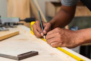 main de charpentier travaillant sur une table d'atelier à l'aide d'outils de mesure photo
