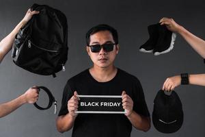 promotion de vente du vendredi noir avec un modèle homme accro du shopping entouré de vêtements noirs et d'accessoires pour homme