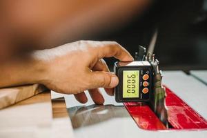 un charpentier utilise un compteur d'angle horizontal ou un inclinomètre numérique pour aligner les lames et les clôtures sur la scie à table à l'atelier, concept de travail du bois. mise au point sélective. photo