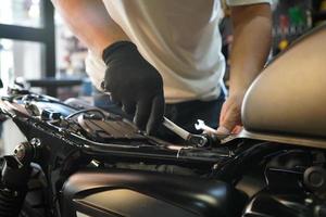 mécanicien utilisant une clé et une douille , travaillant sur une moto dans un garage à moto , concept d'entretien et de réparation de moto. mise au point sélective photo
