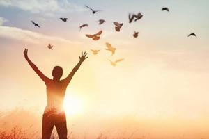 femme priant et oiseau libre profitant de la nature sur fond de coucher de soleil, concept d'espoir photo