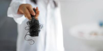 femme perdant ses cheveux sur la brosse à cheveux à la main, mise au point douce photo