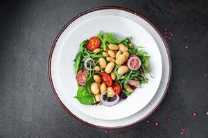 Salade de haricots tomate, oignon, feuilles de laitue mélanger des repas sains et frais collation diététique sur la table copie espace arrière-plan alimentaire régime céto ou paléo photo