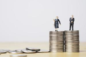 figurine miniature d'homme d'affaires debout sur des pièces égales empilant une femme d'affaires pour l'égalité des sexes homme et femme du concept de revenu et de salaire. photo