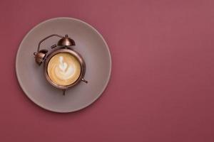 réveil sur une assiette avec du café mousseux et un motif. lever du matin avec du café pour le concept du petit déjeuner. copie espace photo