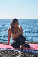 femme latine, d'âge moyen, se reposer, reprendre des forces, manger, boire de l'eau, après une séance de gym, porter un haut orange, brûler des calories, rester en forme, à l'extérieur photo