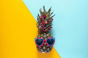 un ananas intelligent dans des lunettes de soleil et des perles lumineuses. concept minimal, ananas tropical d'été. photo