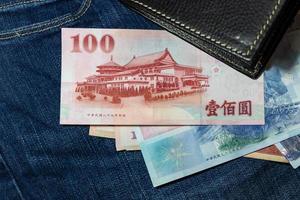 argent taïwanais, billet de banque de taïwan, dollar de taïwan sur fond de jean. photo