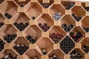 variété de vin dans des bouteilles en verre sur des supports en bois avec des nombres dans un supermarché photo
