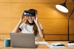 magnifique fille souriante porte un casque vr et une touche interactive par voie aérienne. dispositif de lunettes de casque vr. femme d'affaires asiatique contrôle par réalité virtuelle. photo