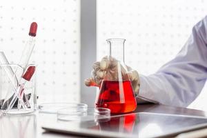 personne en laboratoire, main de scientifique tenant une fiole avec un liquide chimique tombant sur la table, concepts scientifiques et de recherche et développement médicaux