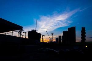 grues de construction industrielle et silhouettes de bâtiments au coucher du soleil photo