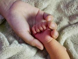 gros plan la main de la mère tient la petite main de son bébé. concept de garde d'enfants, sentiment de sécurité, amour des parents. photo