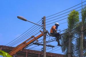 vue en angle bas d'un camion-grue soulevant un électricien monteur pour couper des branches d'arbres trop hautes pour le système de transmission électrique de sécurité et un beau paysage photo