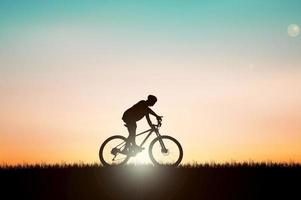 silhouette d'un cycliste dans une belle prairie du soir. idées de vacances à vélo photo