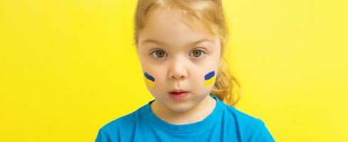 une fille avec un drapeau ukrainien peint en jaune et bleu sur ses joues photo