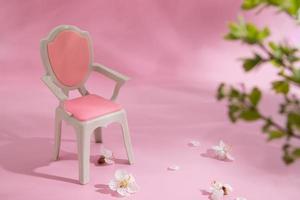 composition abstraite printemps nature morte marionnette chaise avec fleurs blanches et pétales sur fond rose photo