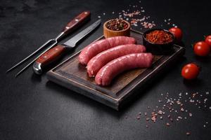 saucisses crues avec des ingrédients sur une planche à découper sur un fond de pierre avec espace de copie photo