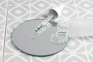 pipette et gouttes de sérum sur miroir, production cosmétique photo