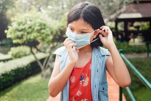 enfants portant une protection faciale en prévention du coronavirus pendant la marche dans le parc photo