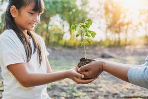 enfants et maman aidant à planter un jeune arbre. concept éco photo