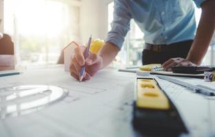 mains d'architecte ou d'ingénieur utilisant un crayon travaillant avec un plan sur le bureau au bureau. outils d'ingénierie et concept de construction. architecte et concept d'entreprise. mise au point sélective, effet vintage. photo