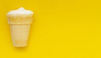 tasse à gaufres de glace à la crème sur fond jaune pastel, espace pour copie. photo