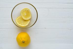 un citron et deux tranches de citron dans une assiette en verre. photo