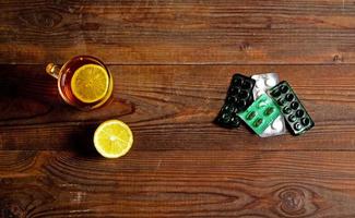 une boisson chaude pour un rhume. automne. maladie. santé. une tasse de thé avec deux morceaux de citron et des pilules froides. photo