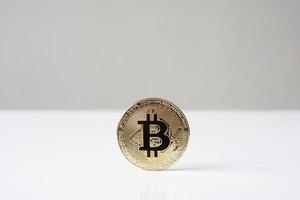 Pièce physique de crypto-monnaie bitcoin debout sur le bureau photo