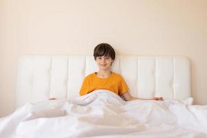 l'enfant s'est réveillé et s'assied sur le lit photo