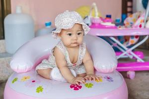 portrait d'une petite fille asiatique regardant ou quelque chose ou sa mère sur une chaise gonflable pendant la pandémie de coronavirus covid-19