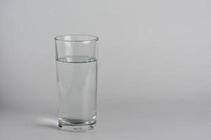 verre avec de l'eau sur une table blanche. photo