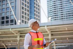 l'ingénieur vérifiant le presse-papiers sur le chantier de construction. le concept d'ingénierie, de construction, de vie urbaine et d'avenir. photo