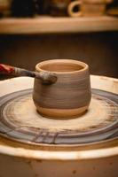 potier travaillant sur un tour de potier avec de l'argile. processus de fabrication de vaisselle en céramique dans un atelier de poterie. photo