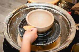 potier travaillant sur un tour de potier avec de l'argile. processus de fabrication de vaisselle en céramique dans un atelier de poterie. photo