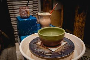 potier travaillant sur un tour de potier avec de l'argile. processus de fabrication de vaisselle en céramique dans un atelier de poterie. photo