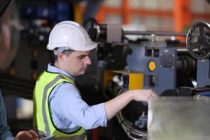 ingénieur industriel hommes portant un casque de sécurité tout en se tenant dans une usine industrielle lourde. la maintenance du travail sur des machines industrielles et la configuration du système de sécurité en usine. photo