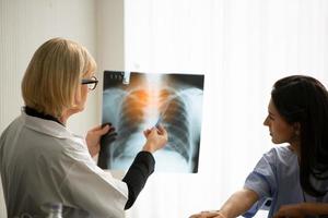 une femme médecin montre l'image d'un film radiographique à une patiente et lui explique. photo