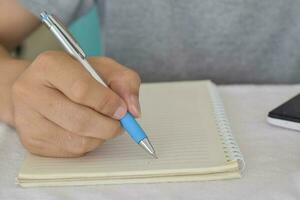 gros plan d'une main masculine avec un stylo écrivant sur un cahier. photo