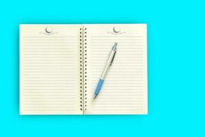 cahier, stylo sur fond bleu. espace de copie vue de dessus