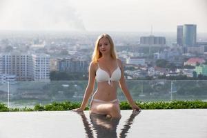 jeune femme profitant d'un soleil, modèle de jeune fille mince en bikini blanc au bord de la piscine. photo