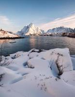 tas de neige avec village de pêcheurs dans la montagne enneigée au littoral photo