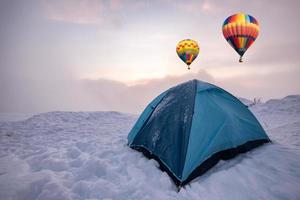 montgolfières colorées volant sur une tente bleue campant sur la colline photo