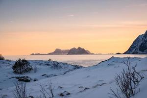 paysage de montagne avec tas de neige sur le littoral le soir en hiver sur les îles lofoten photo