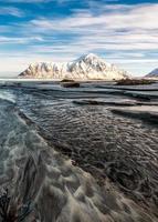 paysage marin de sillons de sable avec montagne enneigée et ciel bleu dans l'océan arctique au lever du soleil matin photo