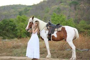 jeune femme avec son cheval dans la lumière du coucher du soleil du soir. photographie en plein air avec une fille mannequin. mode de vie photo