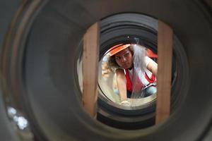 ingénieur industriel féminin portant un casque de sécurité tout en se tenant dans une usine industrielle lourde. la maintenance du travail sur des machines industrielles et la configuration du système de sécurité en usine. photo