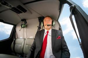 hommes d'affaires voyageant en hélicoptère , photo d'un homme d'affaires mature utilisant un casque lors d'un voyage en hélicoptère