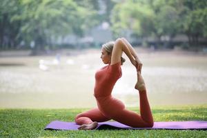 toute la longueur de la femme exerçant le yoga sur un tapis au parc photo